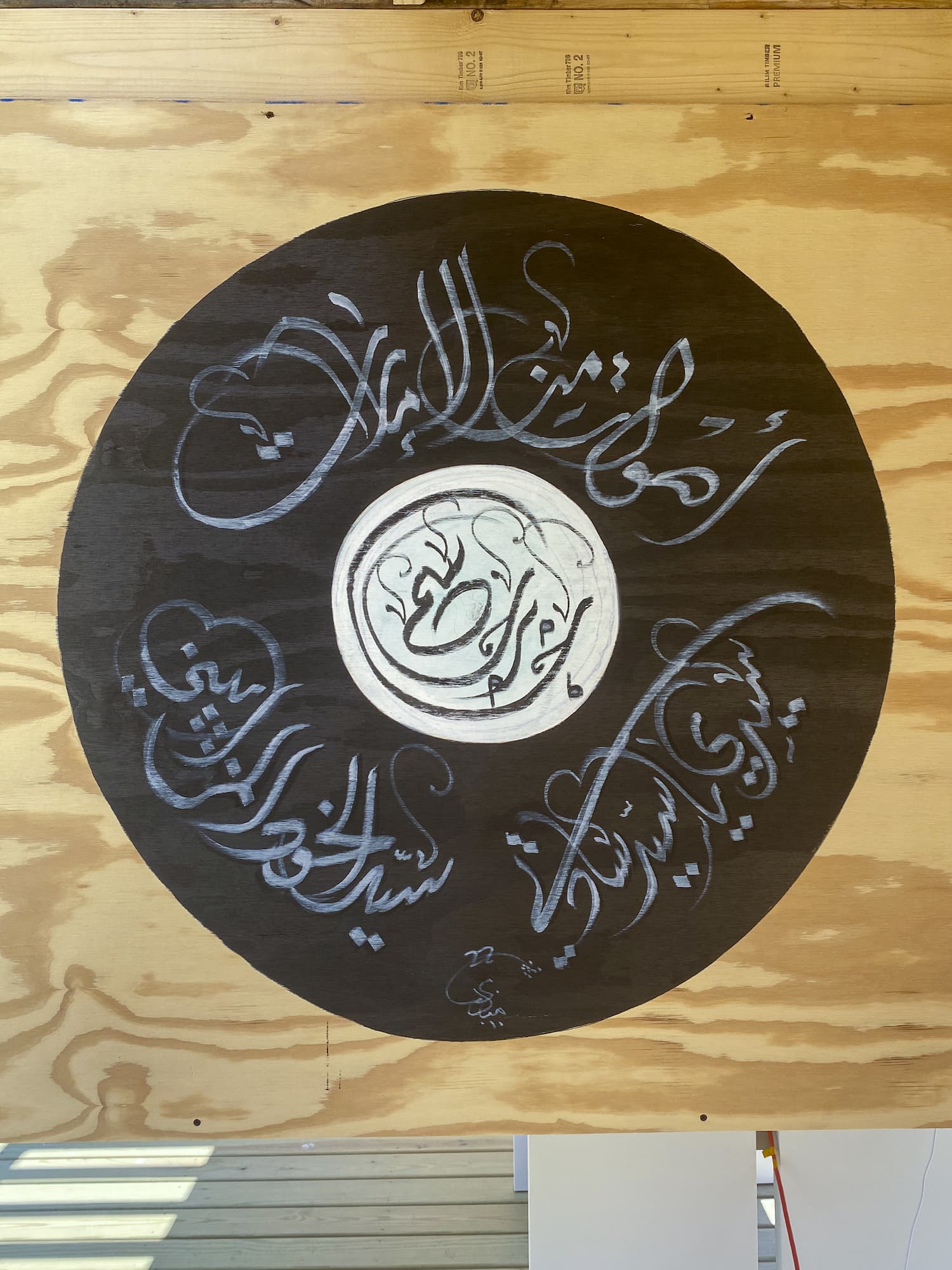 Round piece of artwork hanging on the wall with Arabic script
