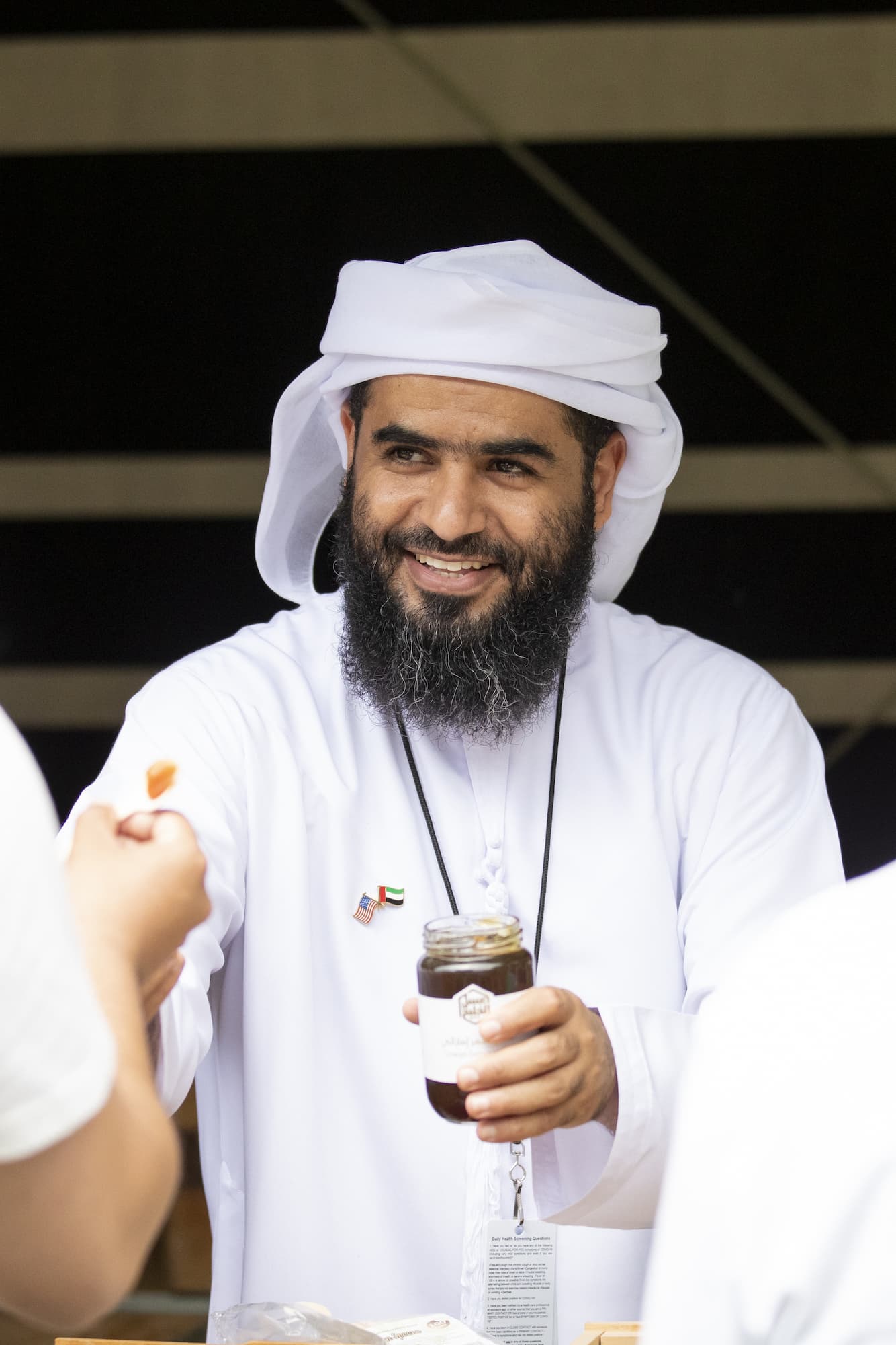 Manea Al Kaabi smiling, holding a jar of honey