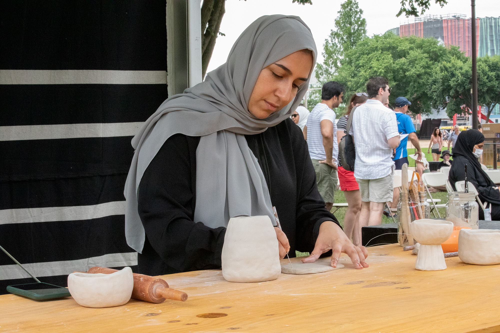 Woman using a pottery tool to sculpt clay