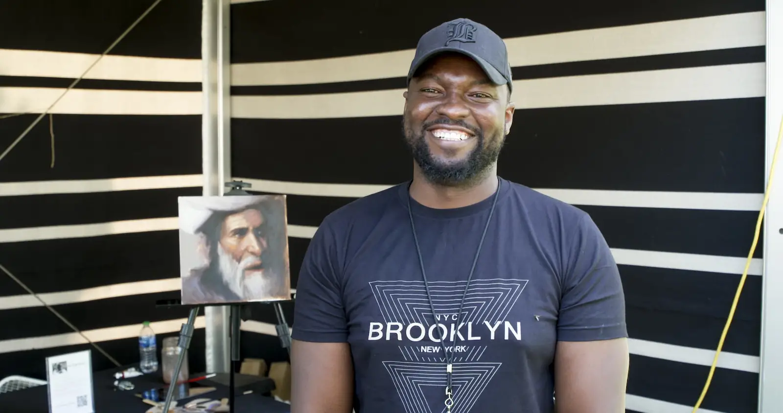 Man wearing a baseball cap and "Brooklyn" T-shirt smiling at the camera