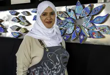 Women in a white head scarf and blue apron standing in front of an art display