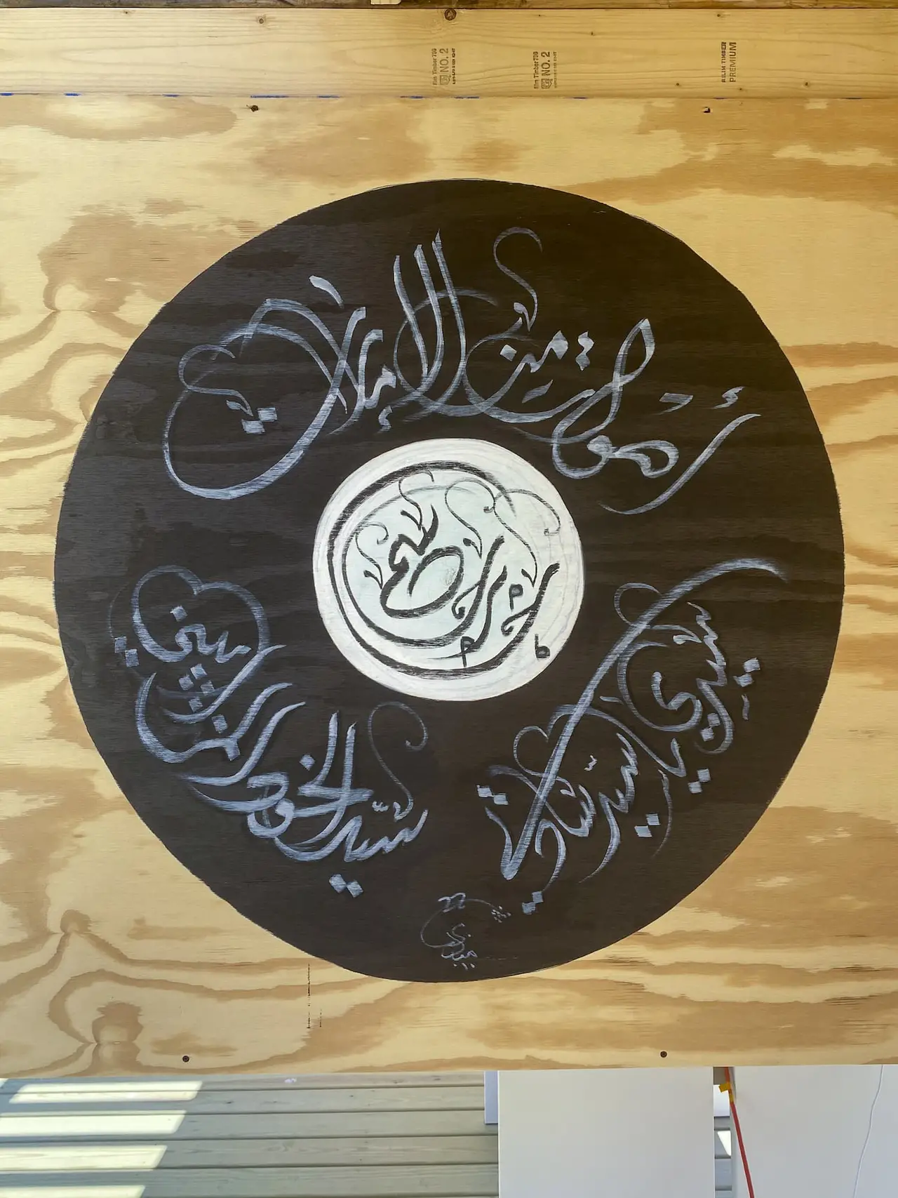 Round piece of artwork hanging on the wall with Arabic script
